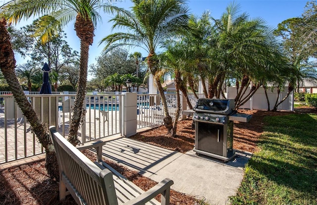 view of patio featuring a community pool, fence, and area for grilling