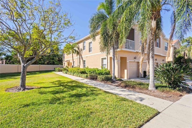 view of front of property with a garage, driveway, stucco siding, fence, and a front yard