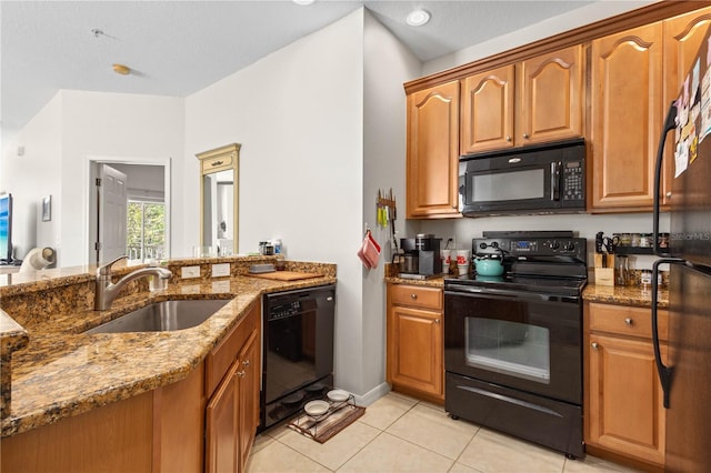 kitchen with stone countertops, light tile patterned flooring, a sink, and black appliances