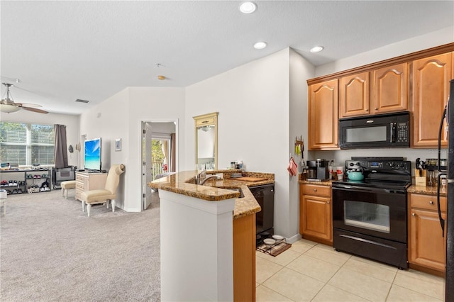 kitchen with open floor plan, a peninsula, light stone countertops, black appliances, and a sink