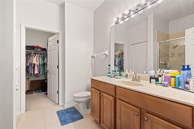 full bath featuring a stall shower, toilet, tile patterned floors, a spacious closet, and vanity