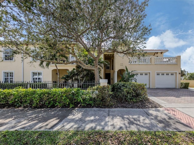 view of front of house with decorative driveway, fence, a balcony, and stucco siding