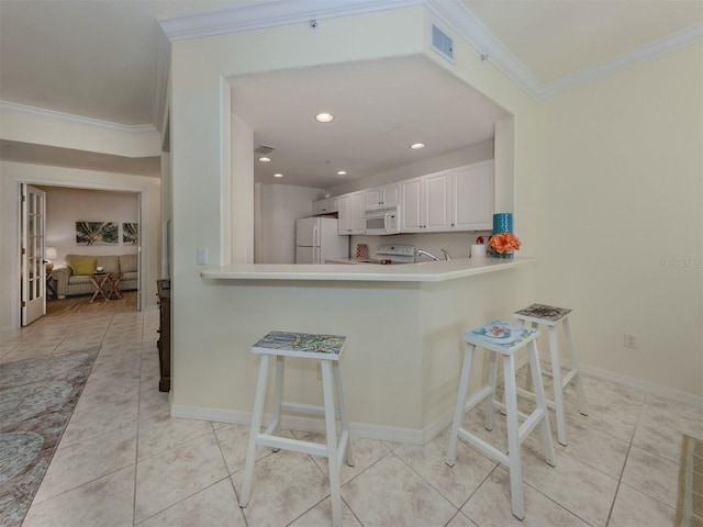 kitchen featuring ornamental molding, a breakfast bar, white appliances, and light tile patterned floors