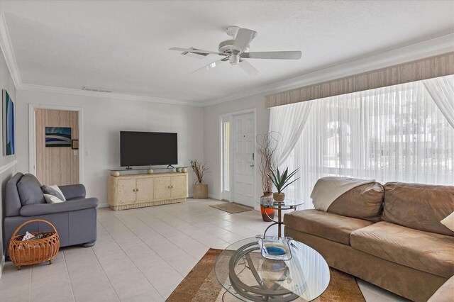 living room with ceiling fan, light tile patterned flooring, visible vents, baseboards, and crown molding