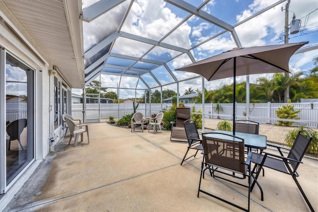 view of patio featuring outdoor dining space, glass enclosure, and a fenced backyard