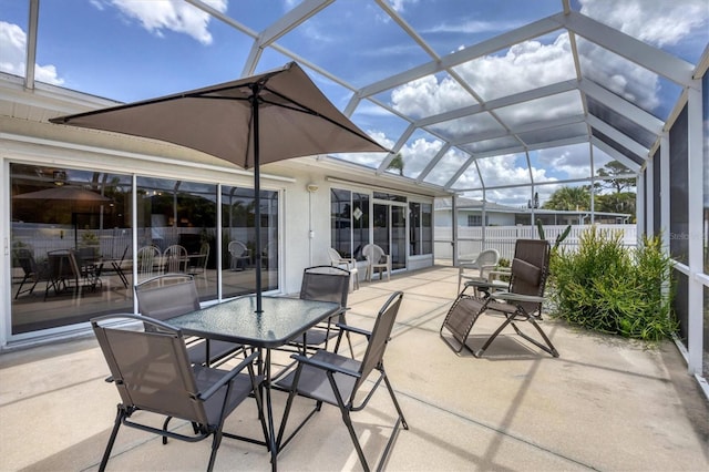 view of patio with a lanai, fence, and outdoor dining area