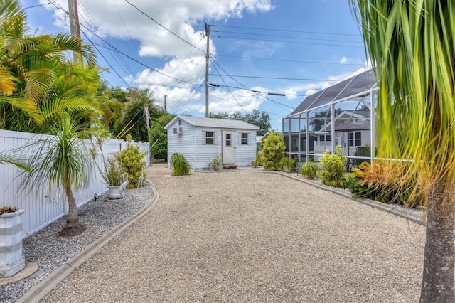 view of yard featuring an outbuilding, glass enclosure, gravel driveway, and fence private yard