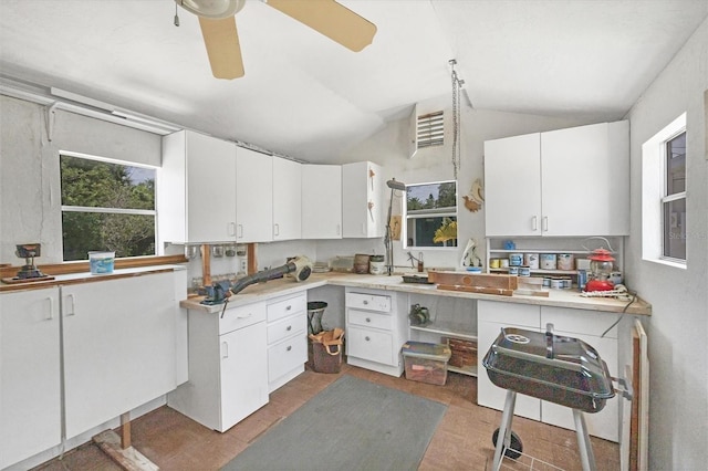 kitchen featuring a ceiling fan, light countertops, white cabinets, and vaulted ceiling