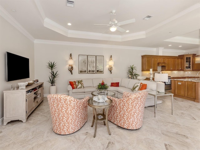 living area featuring a tray ceiling, visible vents, and crown molding