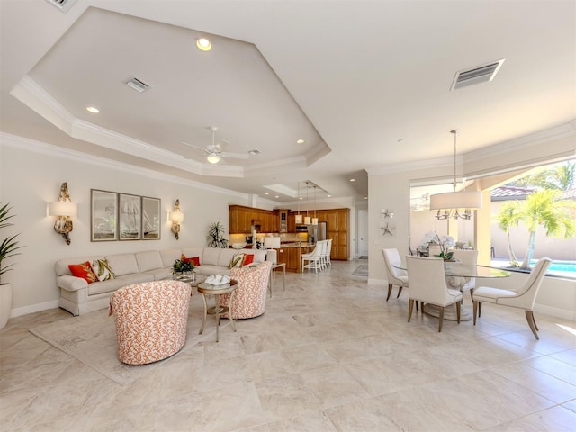 living room with a tray ceiling, crown molding, and visible vents