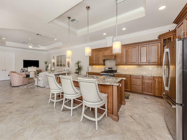 kitchen with a tray ceiling, appliances with stainless steel finishes, brown cabinetry, and visible vents