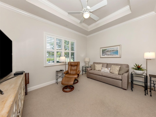 living room featuring ornamental molding, a ceiling fan, a tray ceiling, carpet floors, and baseboards