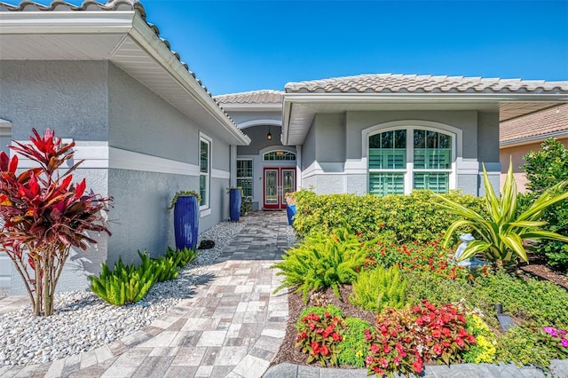 doorway to property with stucco siding, french doors, and a tiled roof