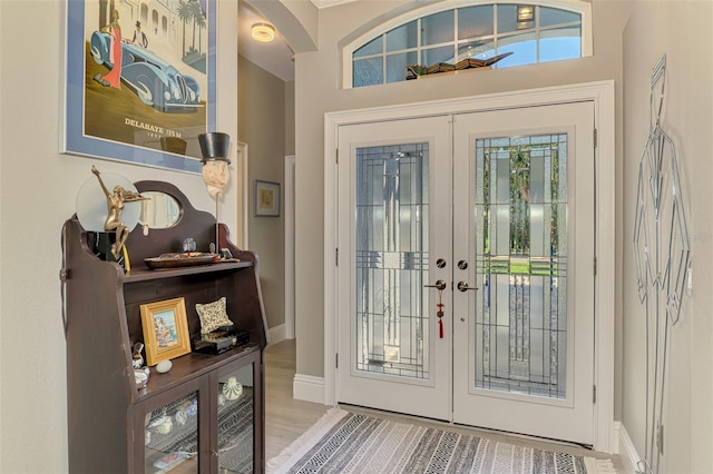 foyer with french doors, wood finished floors, and baseboards