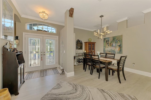 dining area featuring ornamental molding, light wood-type flooring, french doors, and an inviting chandelier