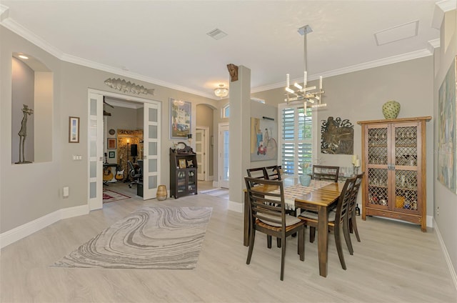 dining space with arched walkways, crown molding, light wood-style flooring, and baseboards