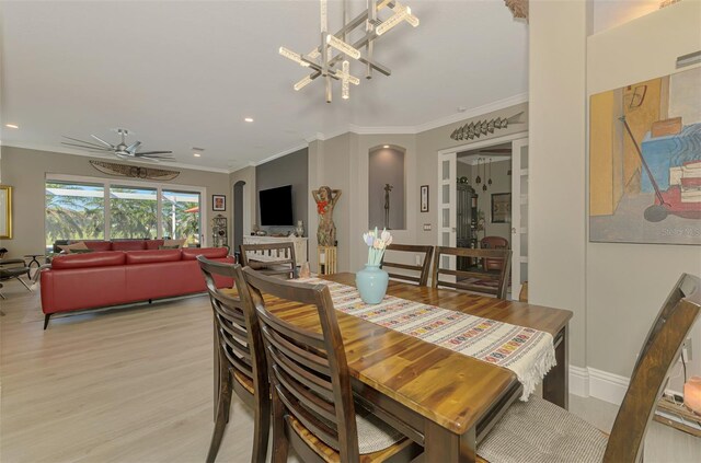 dining space featuring arched walkways, crown molding, recessed lighting, light wood-type flooring, and ceiling fan with notable chandelier