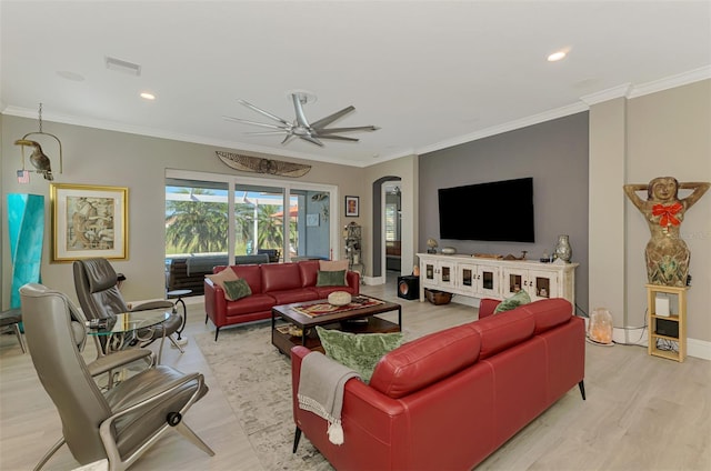 living area with light wood finished floors, visible vents, arched walkways, and ornamental molding