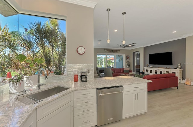 kitchen with arched walkways, white cabinetry, dishwasher, and a sink