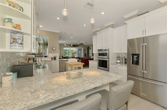 kitchen featuring stainless steel appliances, a peninsula, decorative backsplash, and light stone countertops