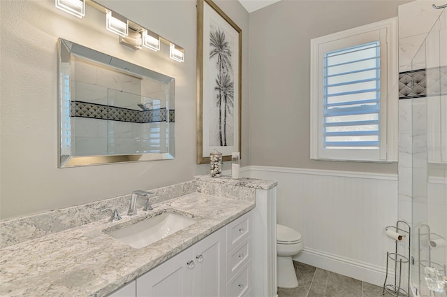 bathroom with toilet, an enclosed shower, wainscoting, vanity, and tile patterned flooring