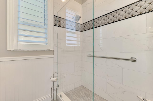 full bath featuring wainscoting and tiled shower