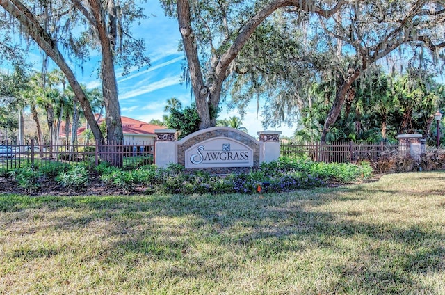 community / neighborhood sign with a lawn and fence