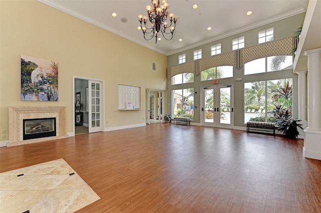 living room with baseboards, a premium fireplace, wood finished floors, crown molding, and french doors