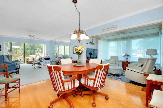 dining space with ceiling fan with notable chandelier, ornamental molding, and light wood finished floors