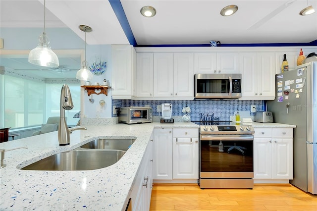 kitchen with light wood-style flooring, a sink, stainless steel appliances, white cabinetry, and tasteful backsplash