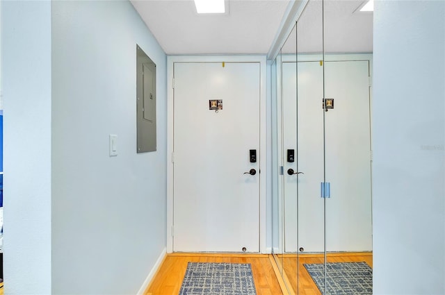 entryway featuring electric panel, baseboards, and light wood finished floors