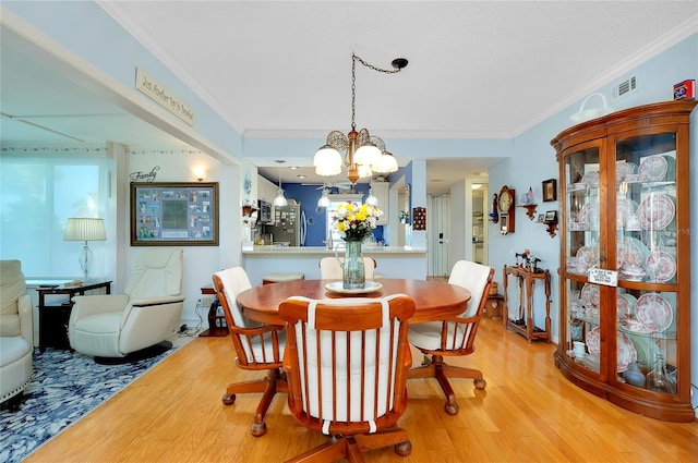 dining space featuring visible vents, an inviting chandelier, crown molding, and light wood finished floors