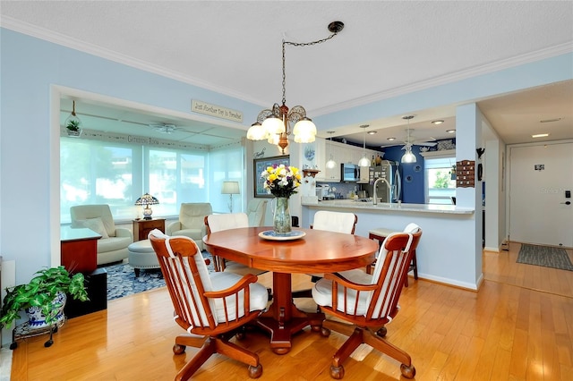 dining space featuring a ceiling fan, light wood-style floors, and ornamental molding