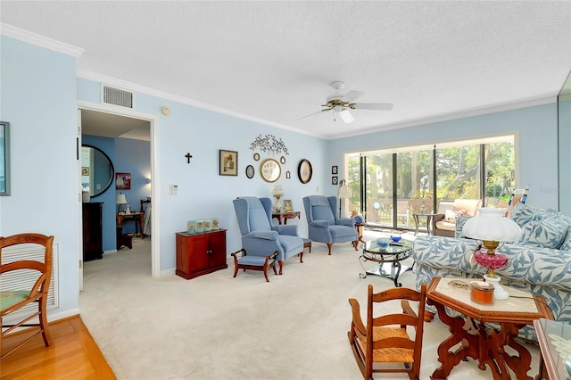 living room with baseboards, visible vents, ceiling fan, ornamental molding, and a textured ceiling