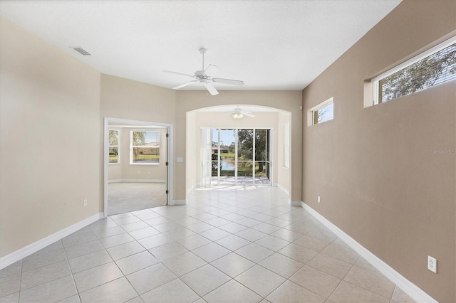 spare room with ceiling fan, light tile patterned floors, plenty of natural light, and visible vents