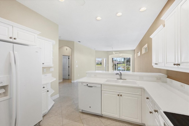 kitchen featuring a peninsula, white appliances, a sink, and light countertops