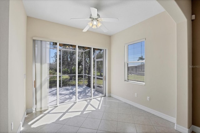 spare room featuring light tile patterned floors, ceiling fan, and baseboards