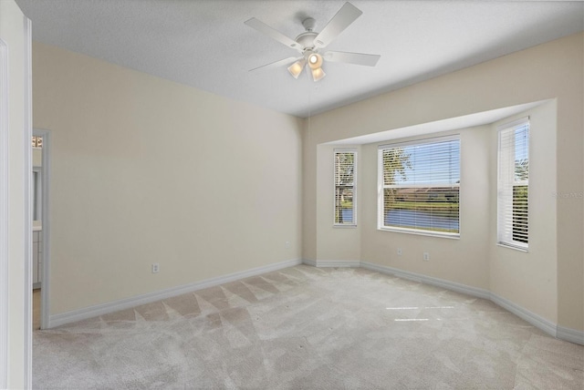 empty room featuring ceiling fan, a textured ceiling, carpet, and baseboards