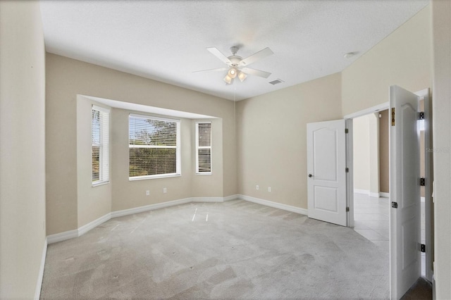 unfurnished room with baseboards, visible vents, a ceiling fan, and light colored carpet