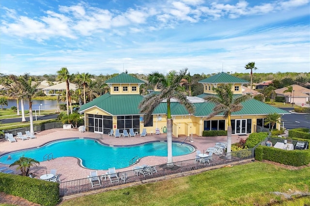 community pool featuring a lawn, a patio area, fence, and a sunroom