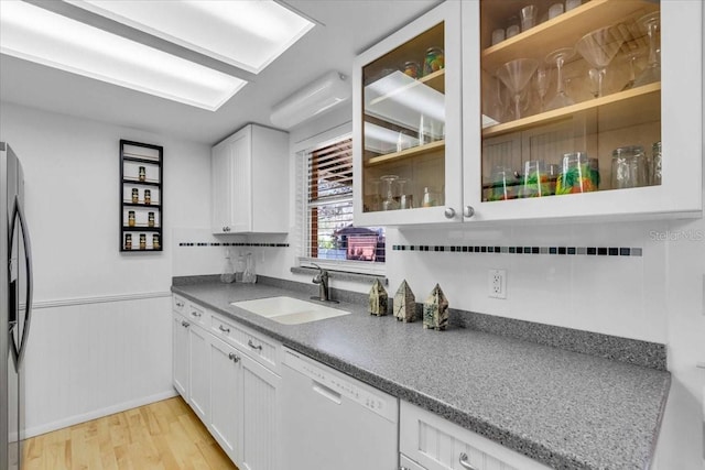 kitchen featuring light wood-style floors, glass insert cabinets, white cabinetry, a sink, and dishwasher