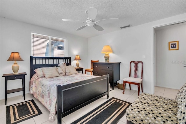 bedroom featuring light tile patterned floors, a ceiling fan, visible vents, and a textured ceiling