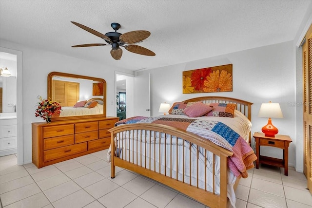 bedroom with light tile patterned floors, ceiling fan, a textured ceiling, and ensuite bathroom