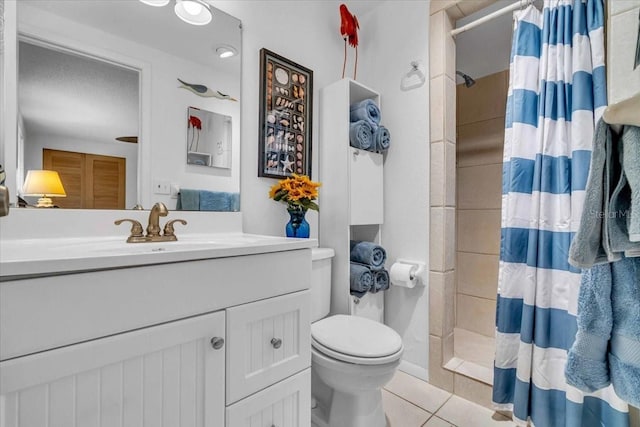 bathroom with tile patterned flooring, a tile shower, vanity, and toilet