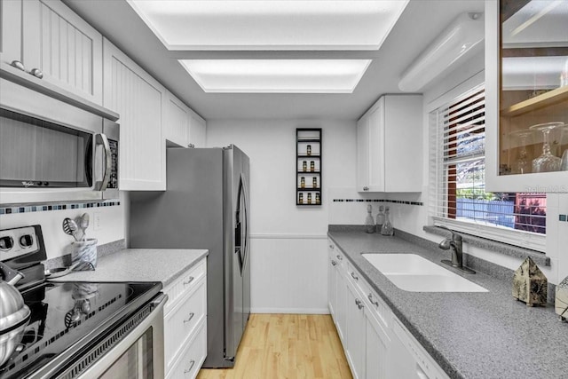 kitchen with light wood-style floors, white cabinetry, appliances with stainless steel finishes, and a sink