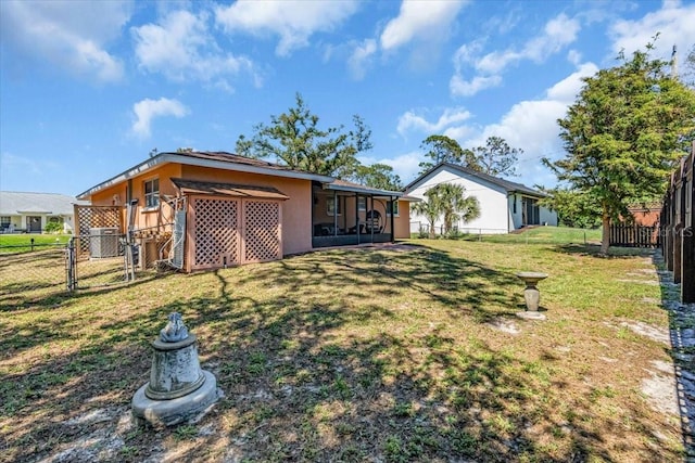 rear view of house featuring a lawn, cooling unit, a fenced backyard, and a sunroom