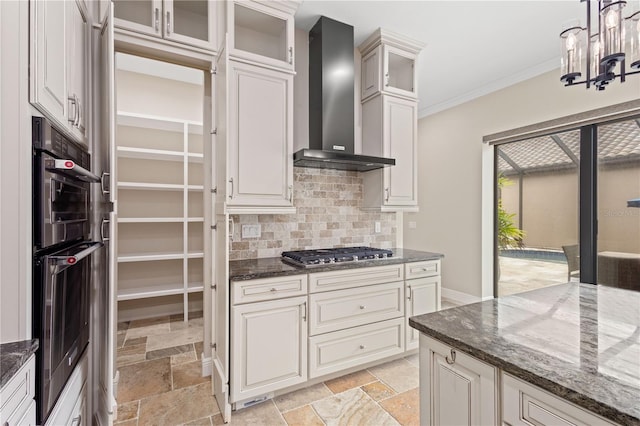 kitchen featuring crown molding, wall chimney exhaust hood, stone tile flooring, and stainless steel gas stovetop