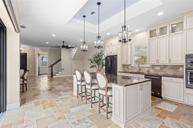 kitchen featuring dishwasher, a tray ceiling, black refrigerator with ice dispenser, and stone tile floors