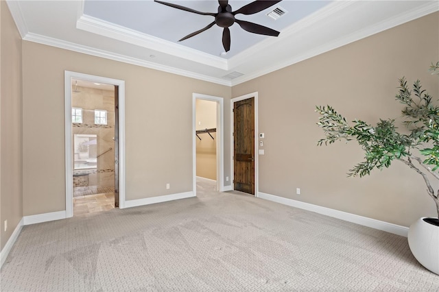 unfurnished bedroom featuring a tray ceiling, carpet flooring, visible vents, and a walk in closet