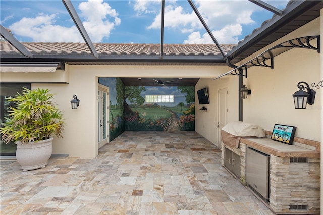 view of patio / terrace featuring exterior kitchen, glass enclosure, and a grill